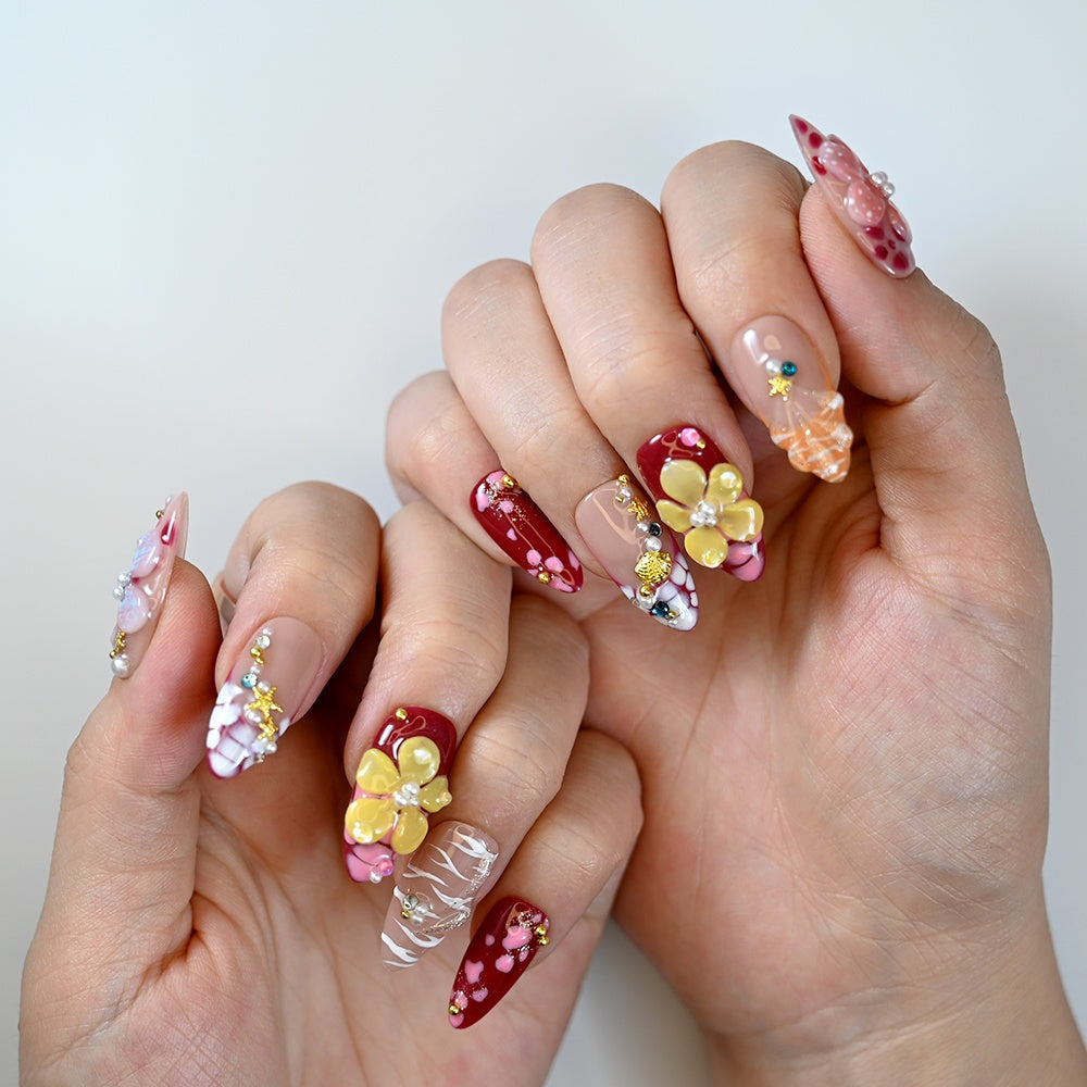 Spring-inspired press-on nails with 3D flower charms, bright colors, and gold accents