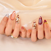 Luxury mixed-media nails with metallic gold texture, pearls, and deep red accents