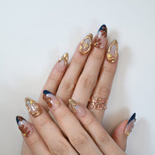 Ocean-inspired press-on nails featuring metallic gold frames and seashell accents