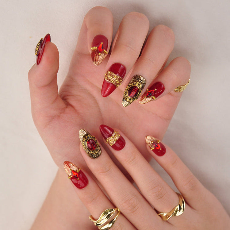 Handmade short nails with ruby red stones, gold detailing, and royal design