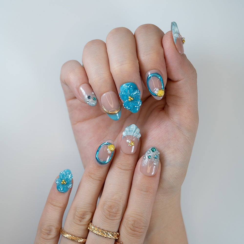 Summer blue nails featuring transparent tips, gold details, and sea elements