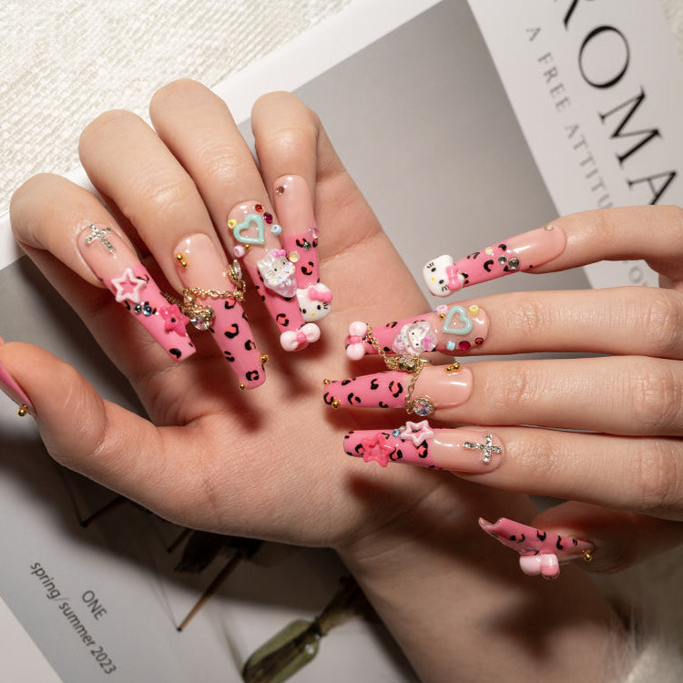 Luxury pink nails featuring animal print design, crystal cross, and hanging chain details
