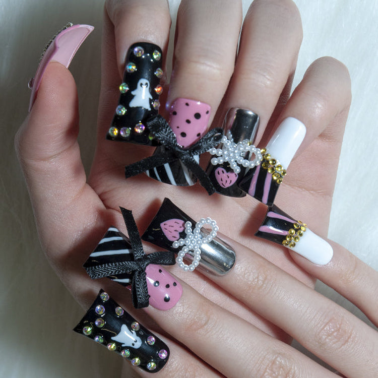 Cute spooky press-on nails with pink polka dots, ghost patterns, and ribbon bows