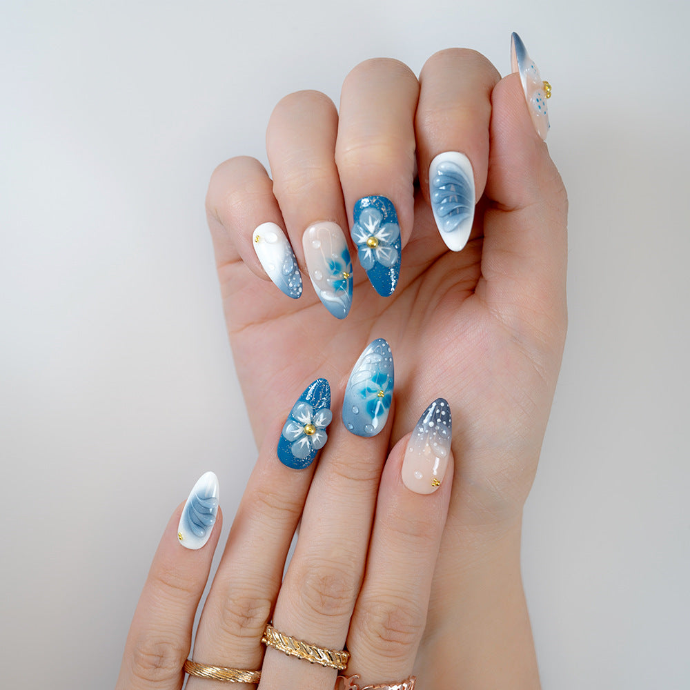  Ocean-inspired almond nails featuring sculpted blue flowers, pearl shimmer, and glossy finish