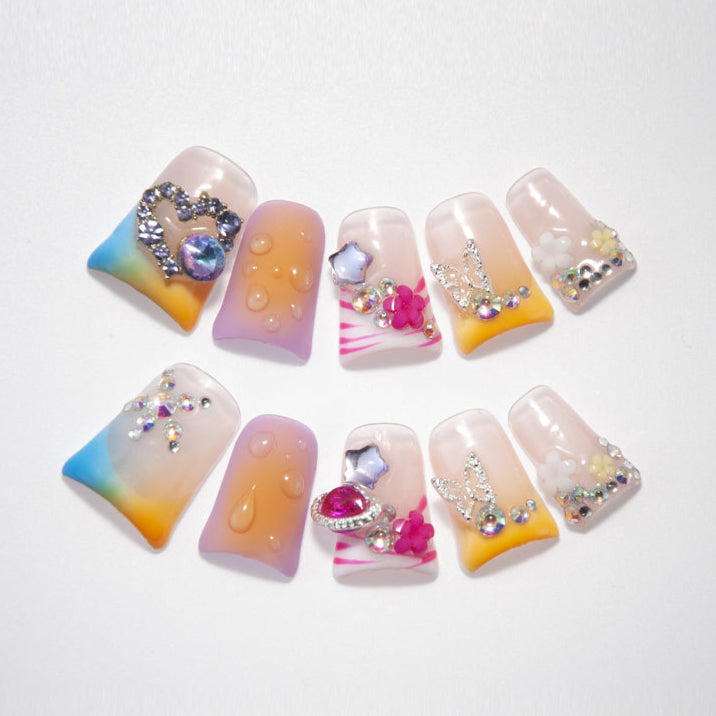 Rainbow gradient press-on nails with rhinestones, heart charm, and 3D flowers