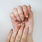 Trendy almond nude press-on nails with cherry gems, floral charms, and animal print tips