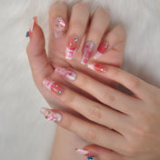 Cute press-on nails with pink and gold glitter, rhinestones, and Hello Kitty art