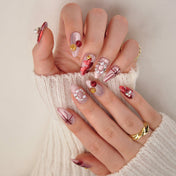 Handmade Christmas nails with metallic red ribbons, pearl accents, and gold star detail