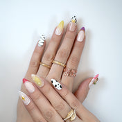 Playful mix-and-match press-on nails with zebra print, cow spots, ombre yellow tips and 3D ice cream charm