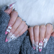 Elegant press-on nails with pink tips, bows, and pearl charms