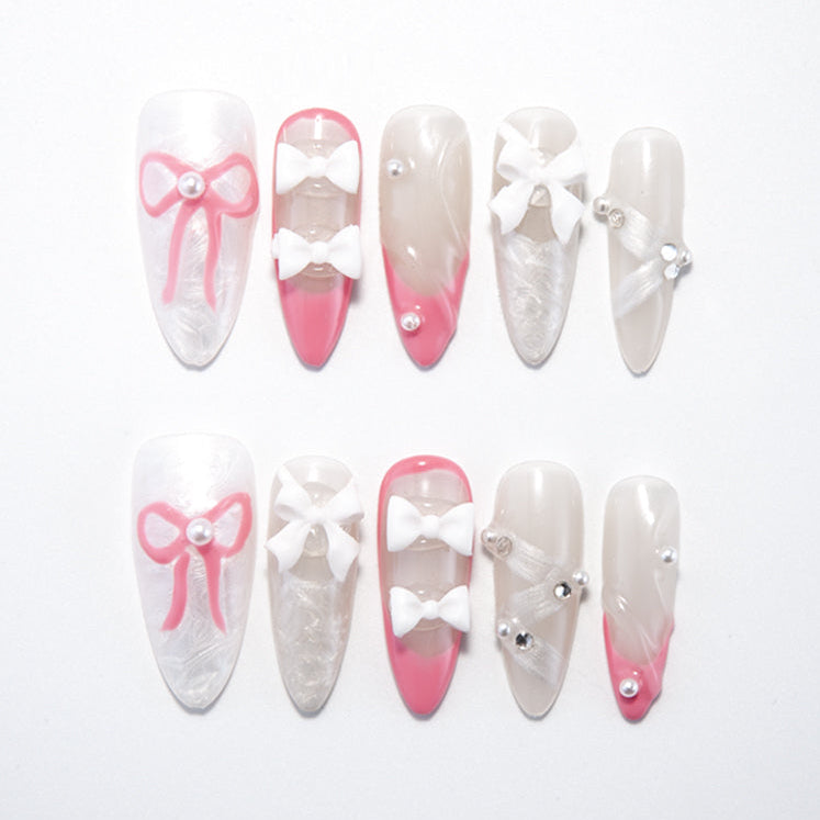 Pink and white press-on nails with 3D bows and pearls