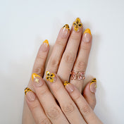 Luxury yellow French tip nails with black tiger stripes and gold embellishments