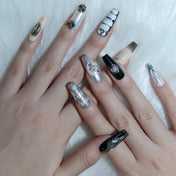 Handmade press-on nails in black, white, and nude with metallic embellishments
