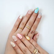 Pastel wave press-on nails in pink, blue, and yellow with pearl accents