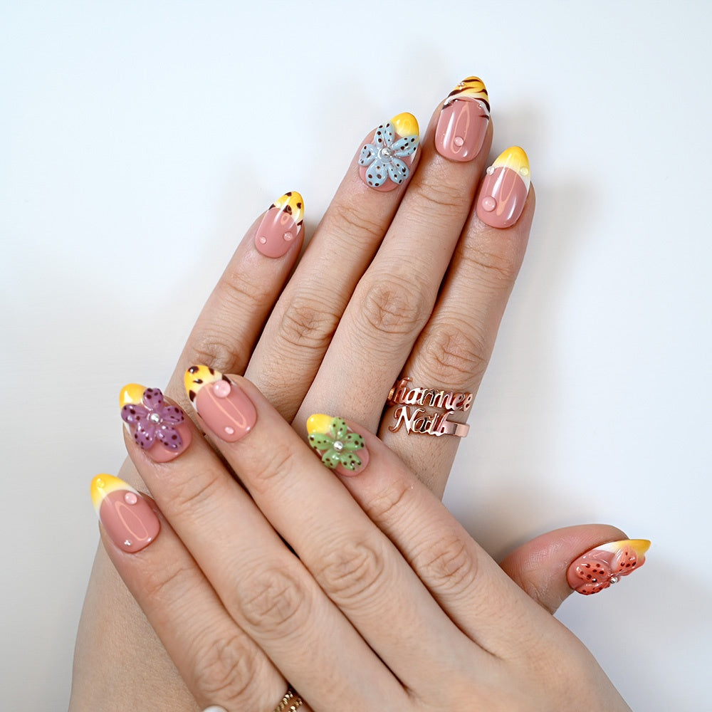 Fruit-inspired press-on nails with yellow French tips, 3D flower accents and glossy finish