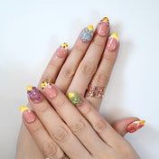 Fruit-inspired press-on nails with yellow French tips, 3D flower accents and glossy finish