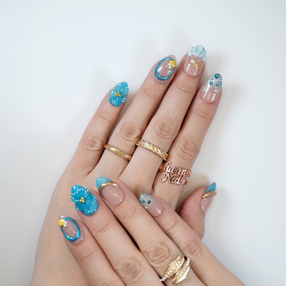 Beach-inspired almond nails in ocean blue with shell and pearl details