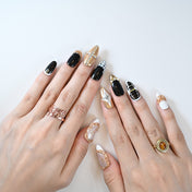 Elegant almond-shaped press-on nails in black and gold with jewel embellishments