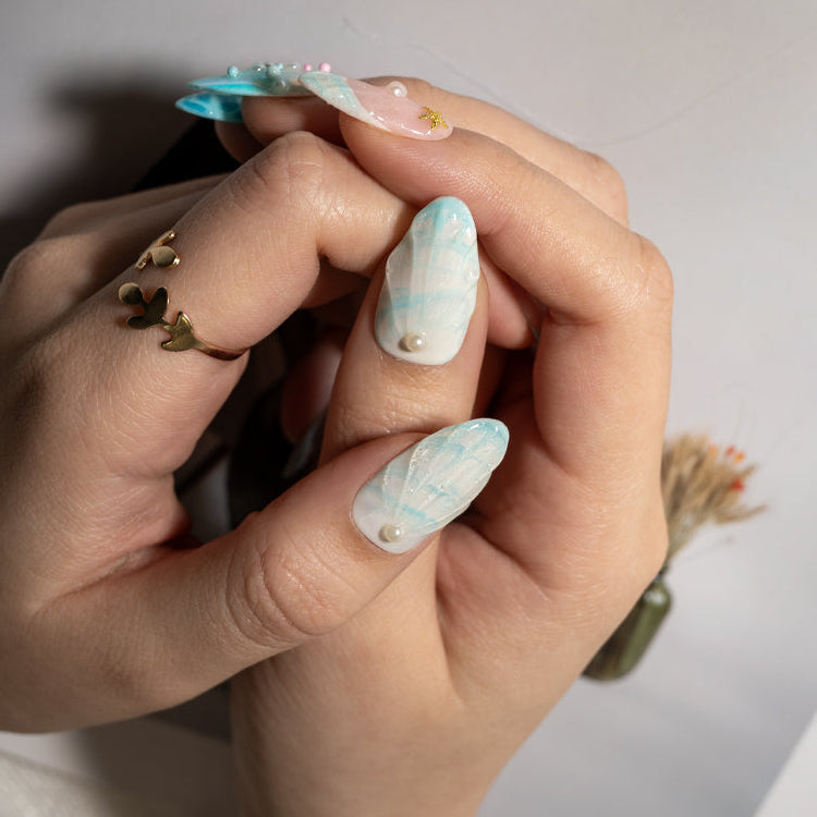 Handmade summer beach nails with shell art, pastel blue tones, and starfish