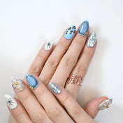 Stylish blue ombre press-on nails with leopard spots, starburst art, and metallic details