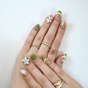Fresh botanical nails featuring translucent green gradient, gold line art, and floral charm