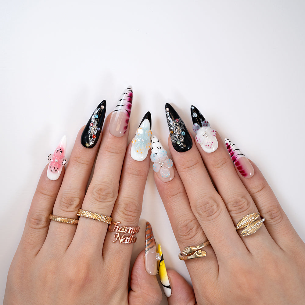 Bold long press-on nails featuring 3D floral designs, stripes, and gemstone accents