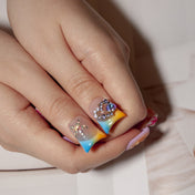 Colorful press-on nails with star charms, pink floral accents, and sparkle