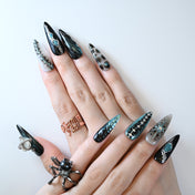 Punk style handmade black nails with silver accents, spikes, and gemstone details