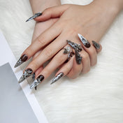 Gothic style nails with silver foil details, angel figurines, and cross charms