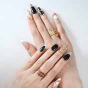 Black, white, and gold press-on nails with 3D metallic accents and crystal gems