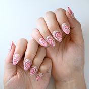 Cute pink press-on nails with sparkling heart patterns and gemstone decorations
