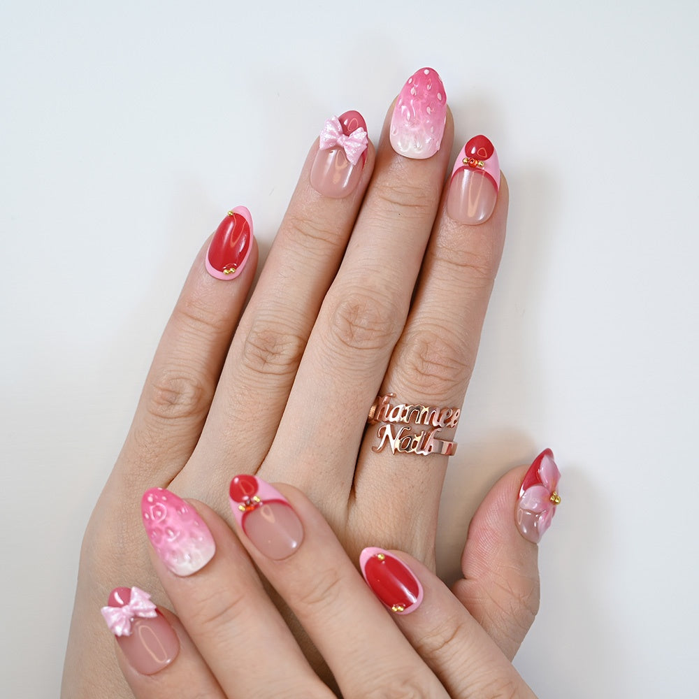 Cute pink and red handmade nails featuring berry texture and girly ribbon accents