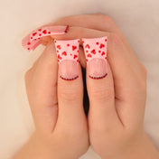 Valentine’s Day nails with cute red hearts, pink base, and beaded accents