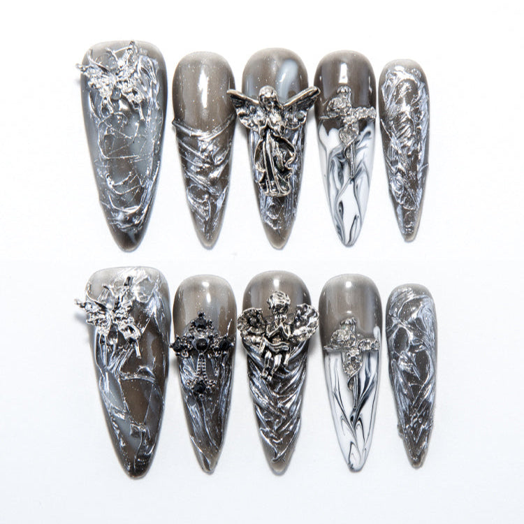 Gray and silver press-on nails with 3D angel charms and gothic cross accents