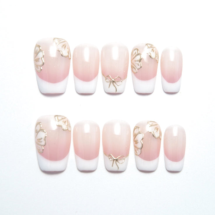 Short  coffin  press-on nails with pink and white French tips, 3D gold butterflies, and bow design