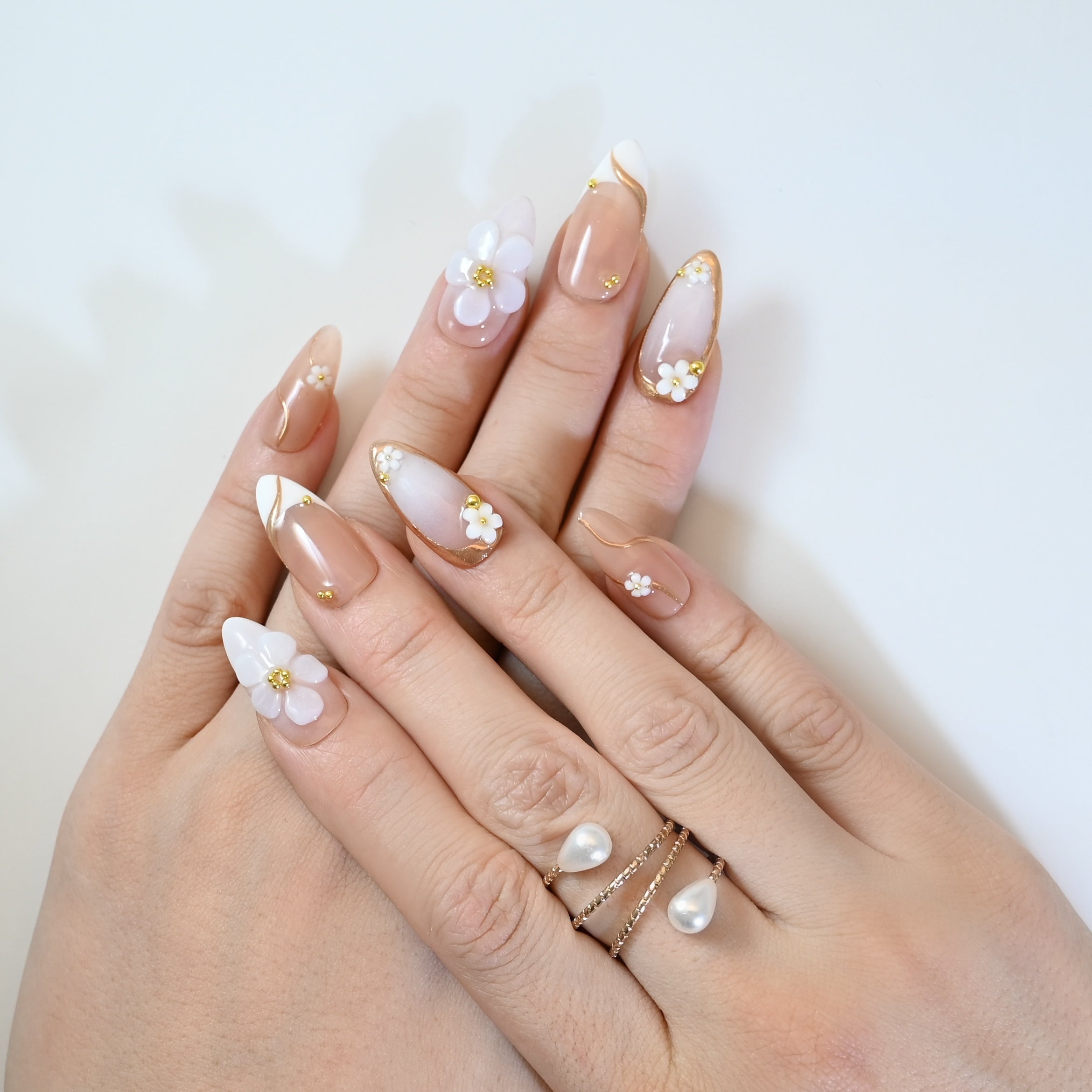 Chic nude press-on nails with gold lining, 3D blossoms, and delicate details