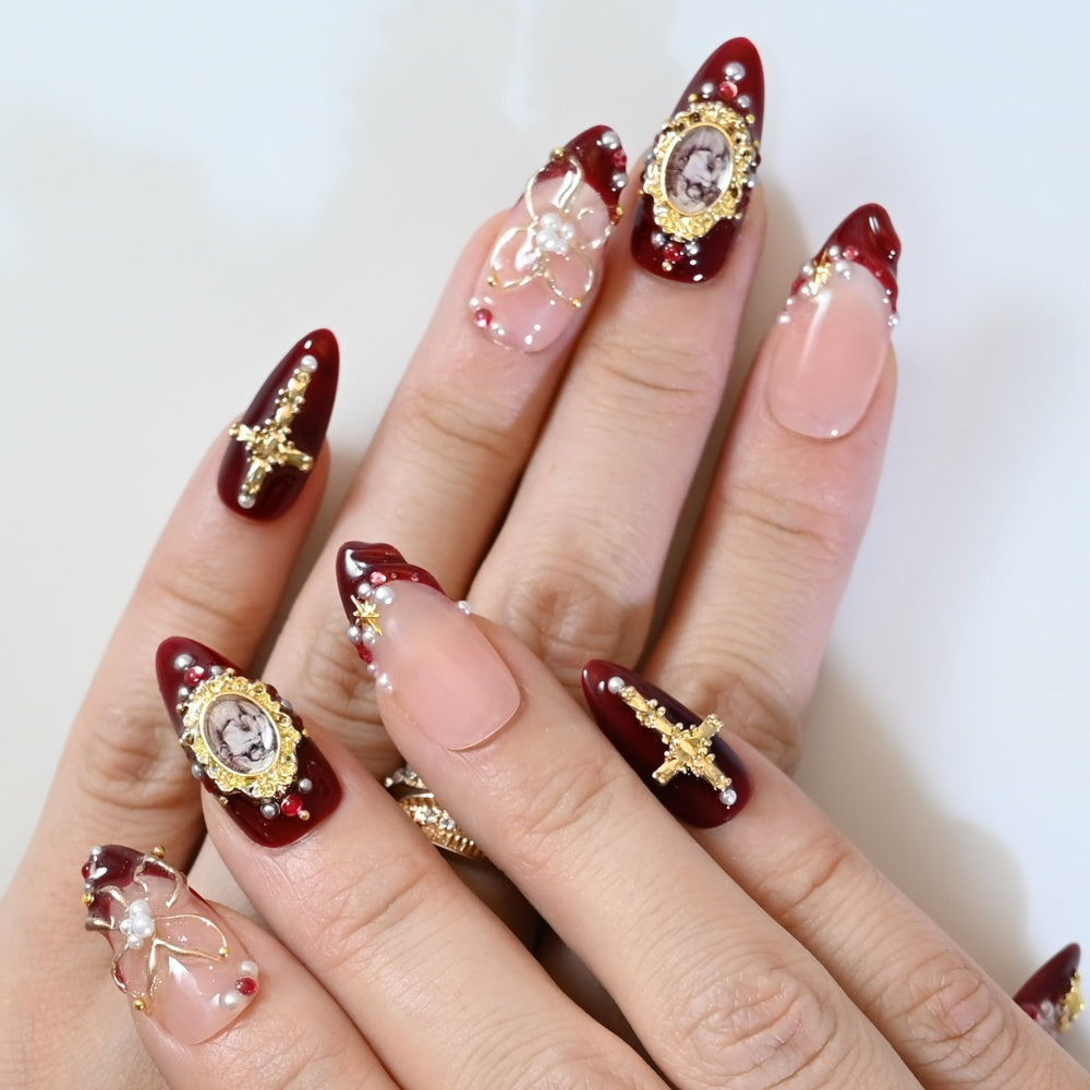 Elegant burgundy and nude press-on nails with 3D pearls, gold metal charms, and antique style