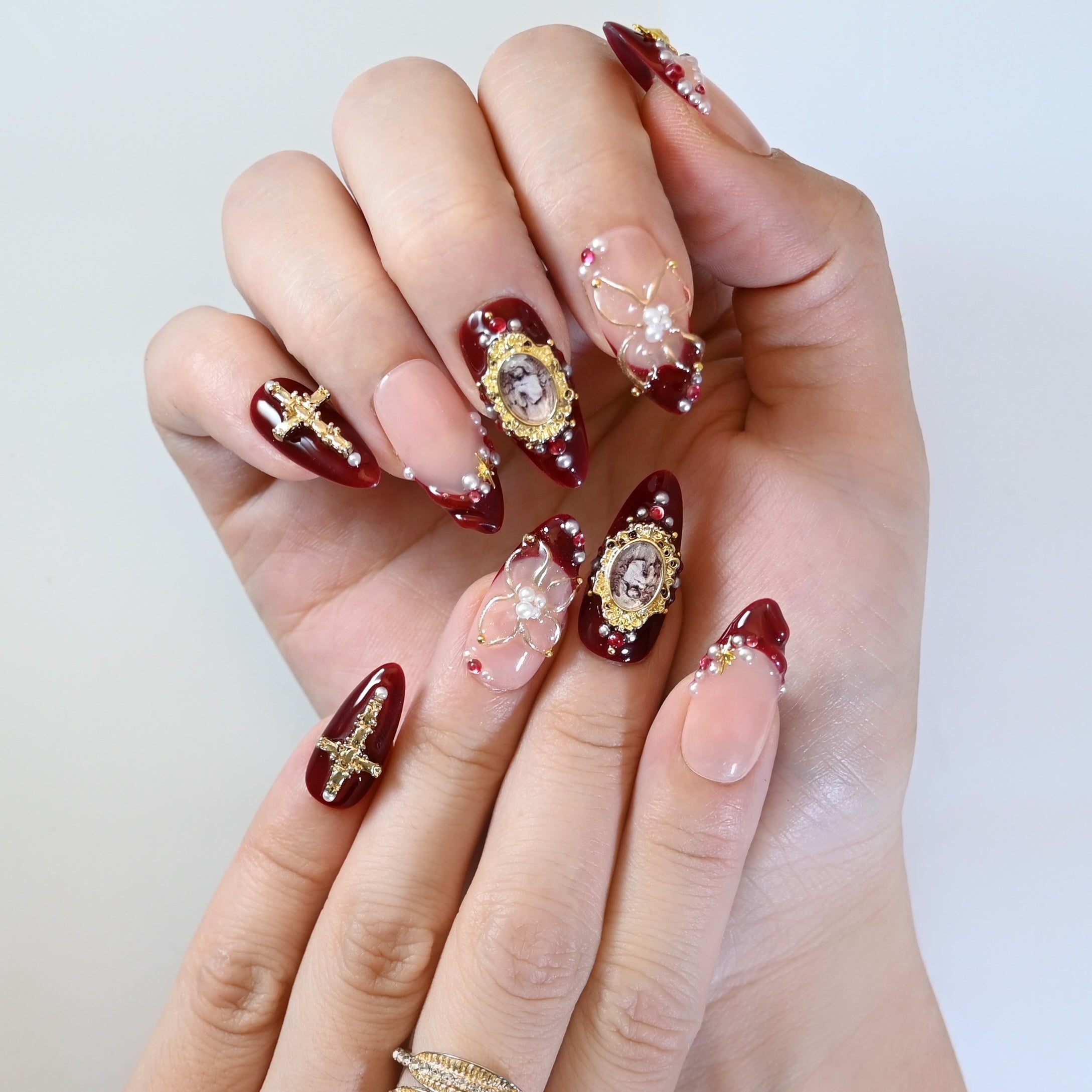 Luxury vintage press-on nails with gold sunburst charm, cross, and cameo centerpiece