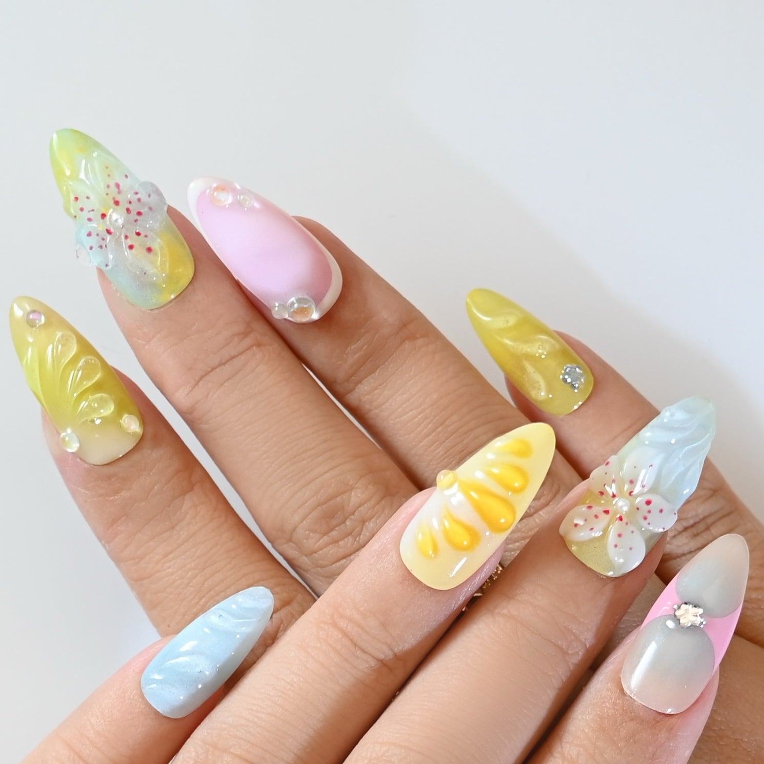 Multi-color press-on nails with hand-sculpted flowers, gradient tones, and sparkle