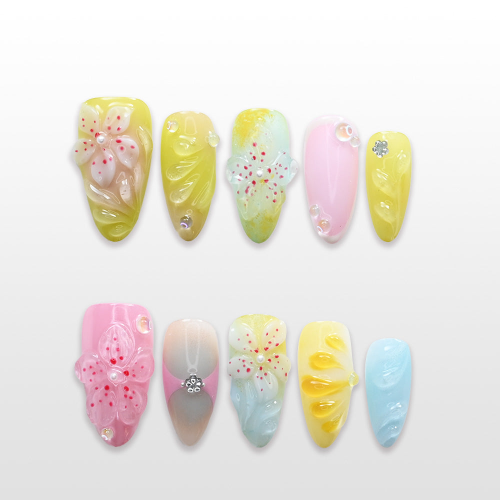Pastel yellow, pink, and blue press-on nails with 3D floral carvings and rhinestones