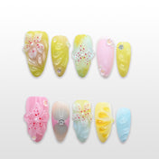 Pastel yellow, pink, and blue press-on nails with 3D floral carvings and rhinestones