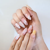 Romantic press-on nails with gradient pink-yellow base, floral accents, and pearls