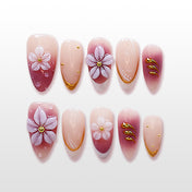 Pink to purple gradient press-on nails with 3D white floral design and gold accents