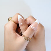 Classy almond-shaped French nails with pearl details and silver cross design