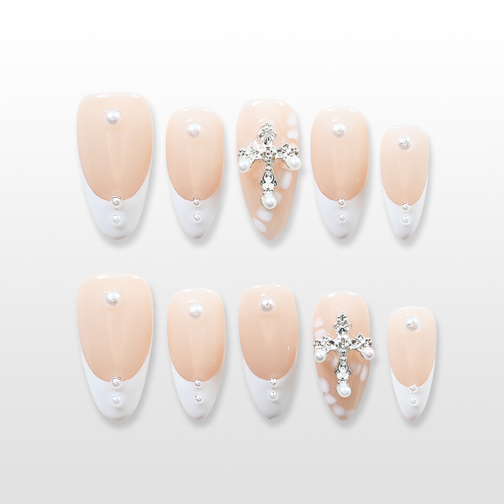 Elegant French tip press-on nails with nude base, pearls, and cross embellishment