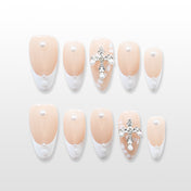 Elegant French tip press-on nails with nude base, pearls, and cross embellishment