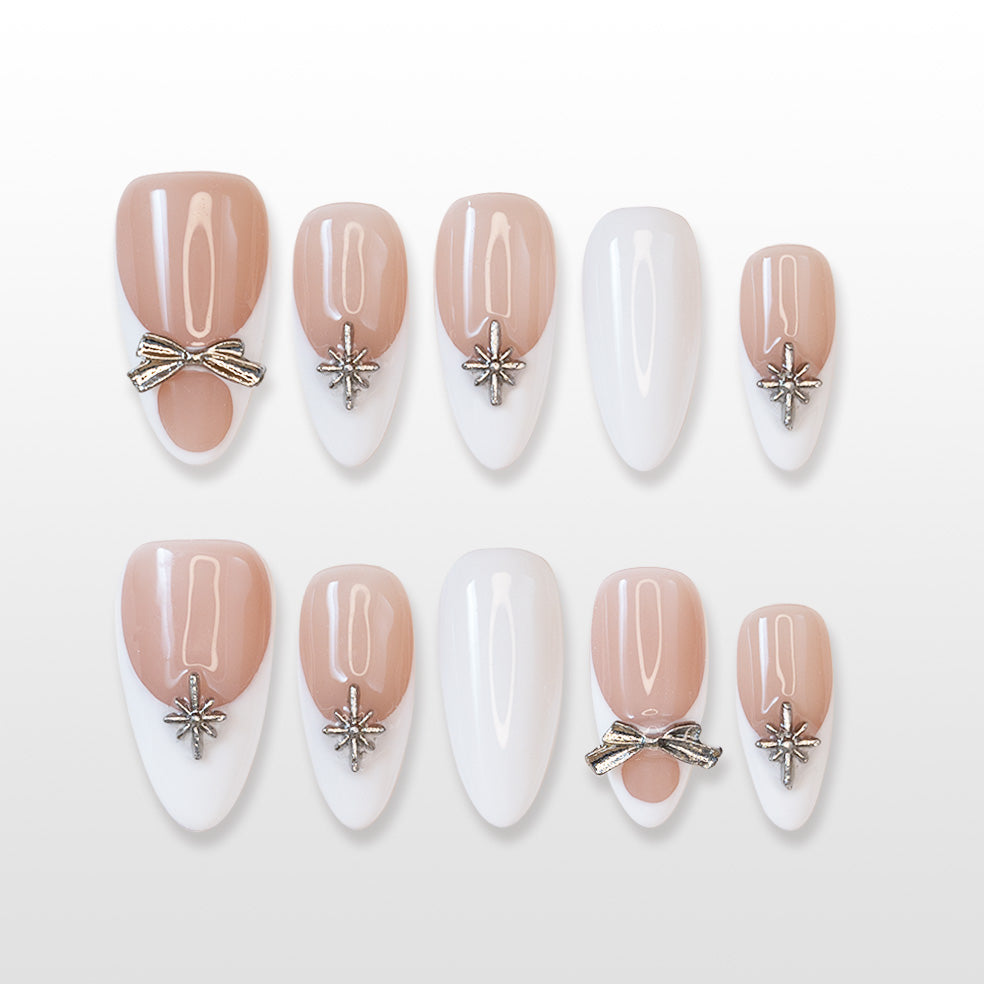 Nude and white French press-on nails with silver bow charm and star embellishments