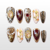 Vintage royal style press-on nails with gold frames, pearls, and gemstone accents