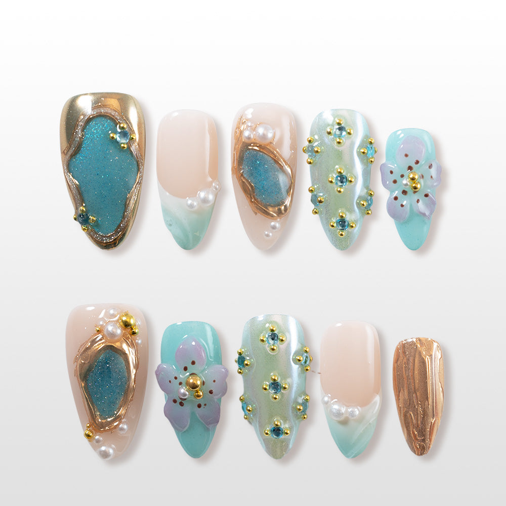 Ocean-inspired press-on nails with 3D floral designs, blue rhinestones, and pearl details