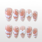 Nude pink press-on nails with white floral lace and 3D bow accents